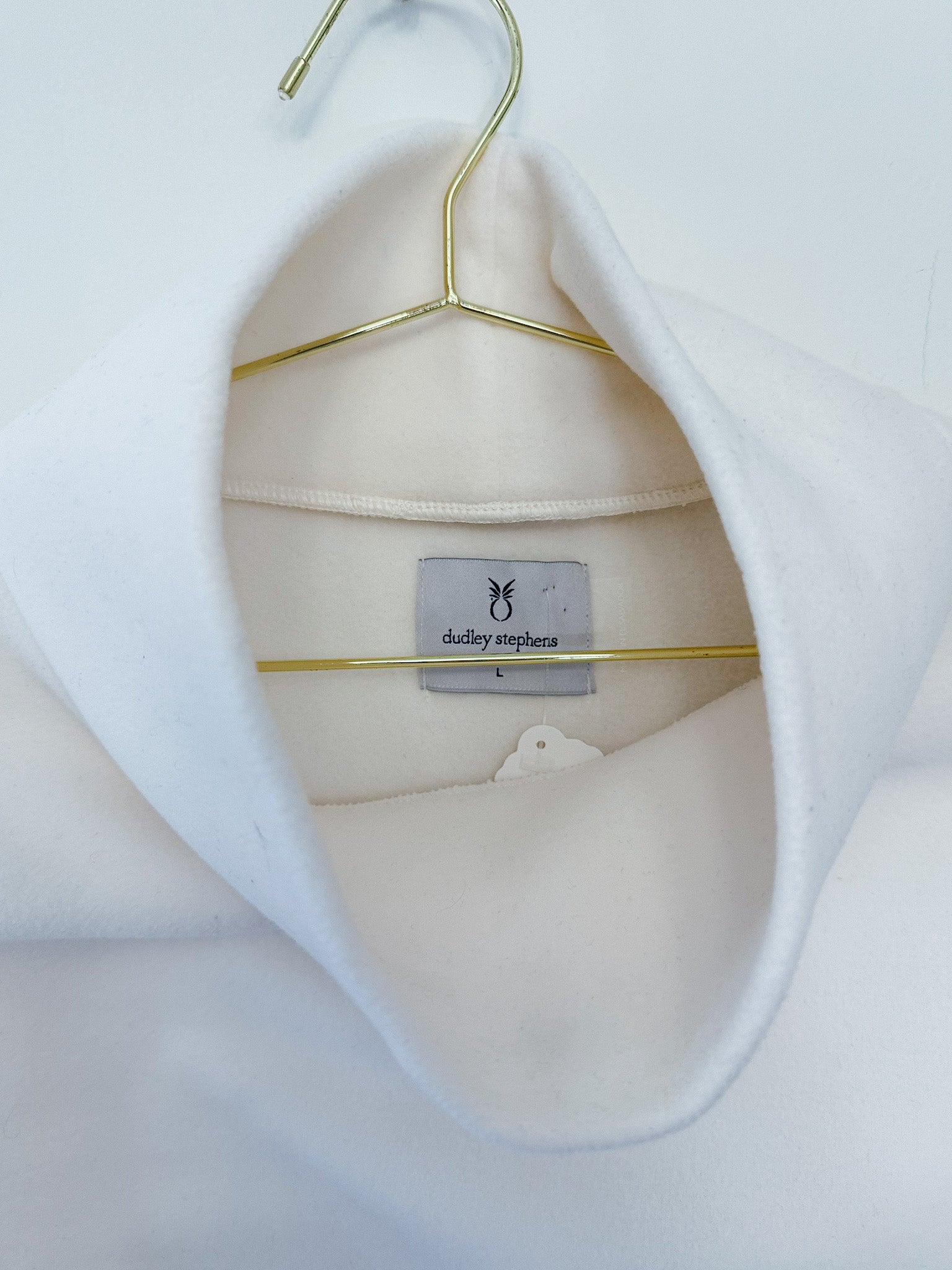 White shirt on a gold hanger with a visible brand label against a white background