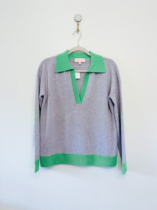 Gray sweater with green collar and cuffs on a hanger against a white background