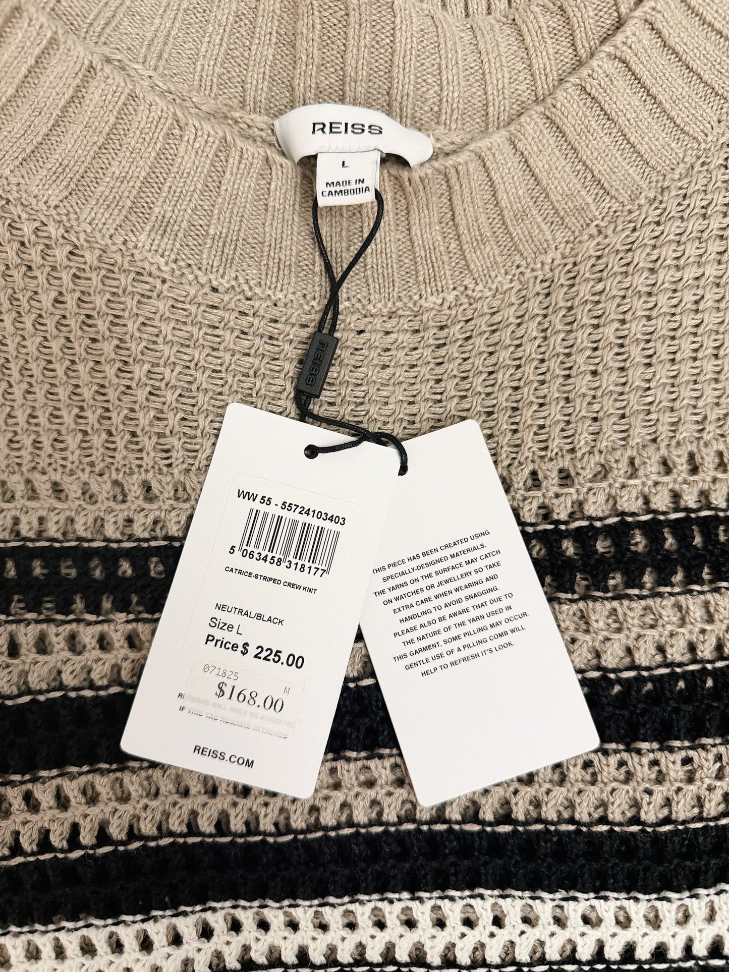 Beige sweater with a REISS tag showing price and size information.