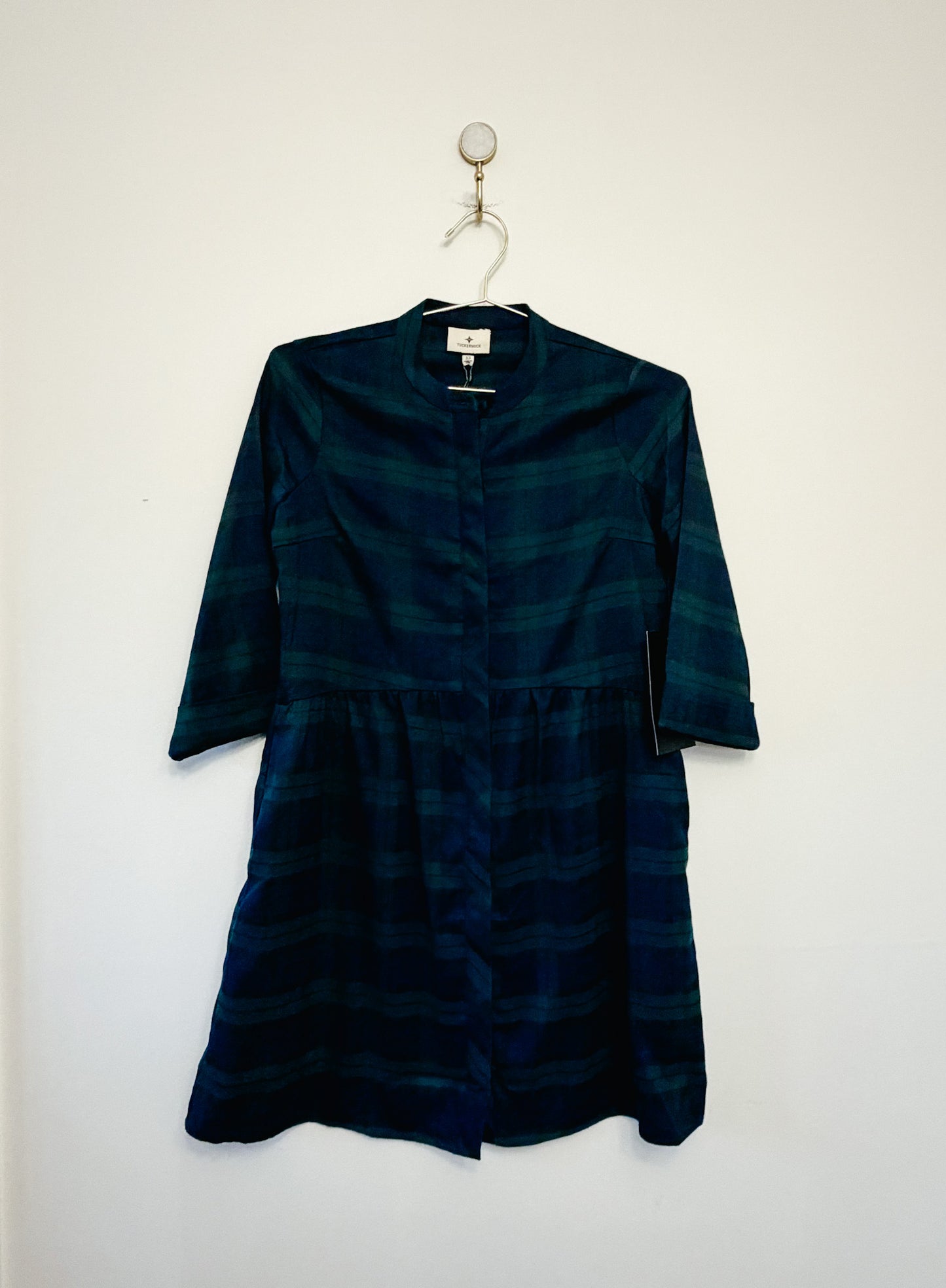 Dark green dress on a hanger against a white background