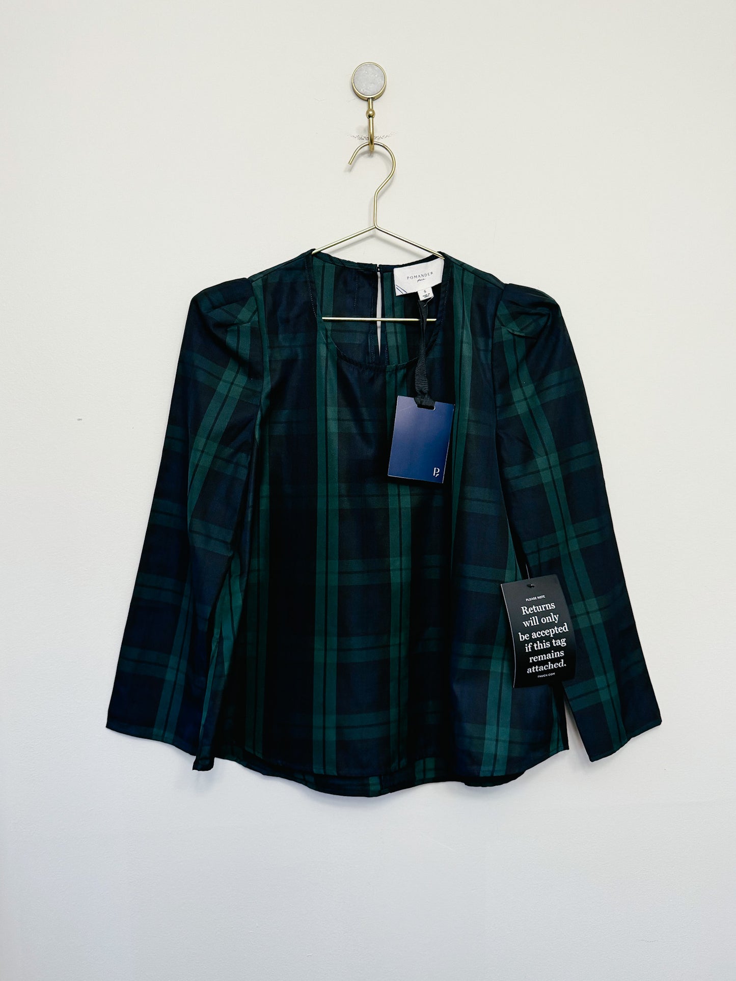 Green plaid shirt on a hanger against a white background