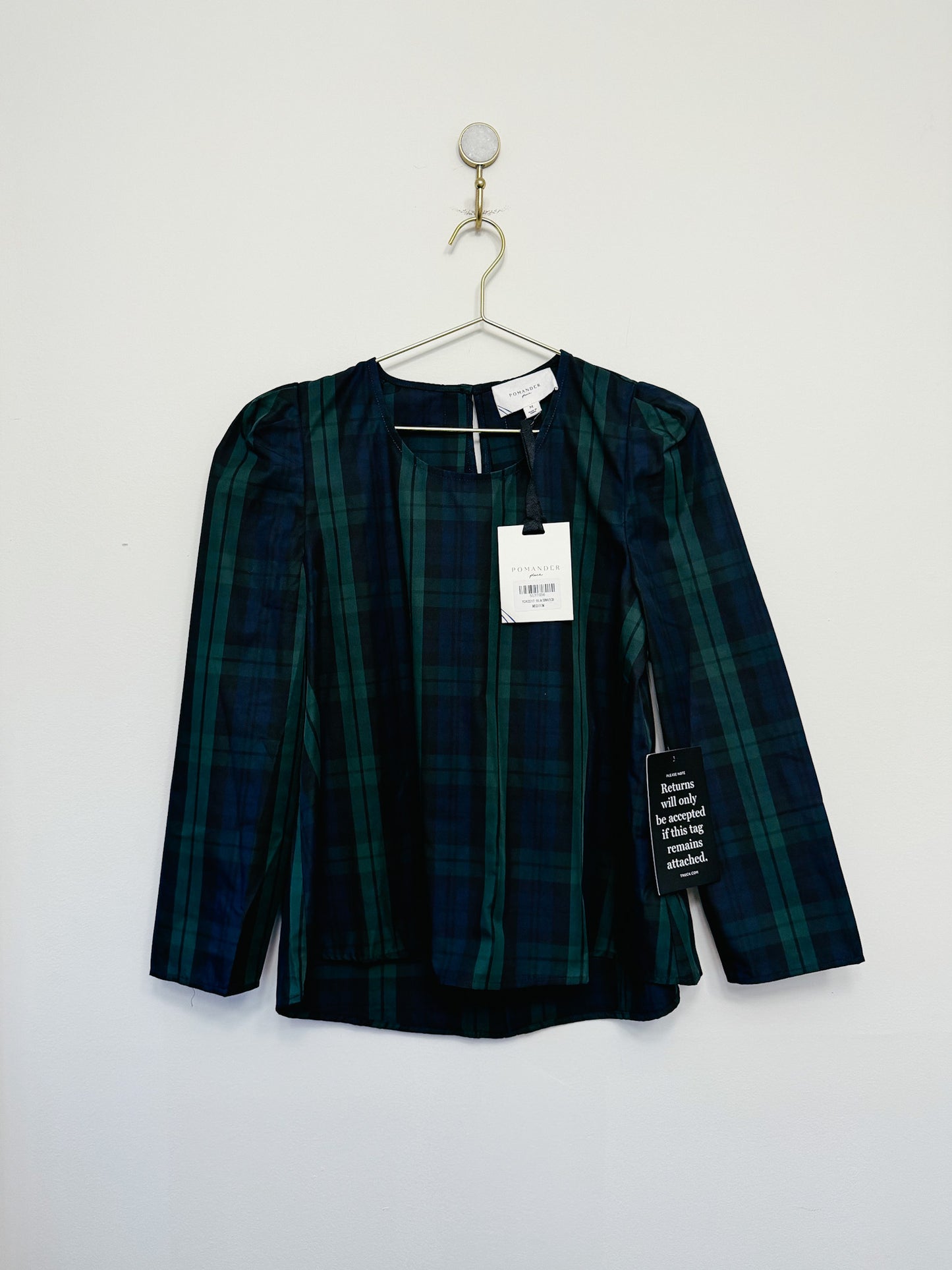 Green plaid shirt on a hanger against a white background