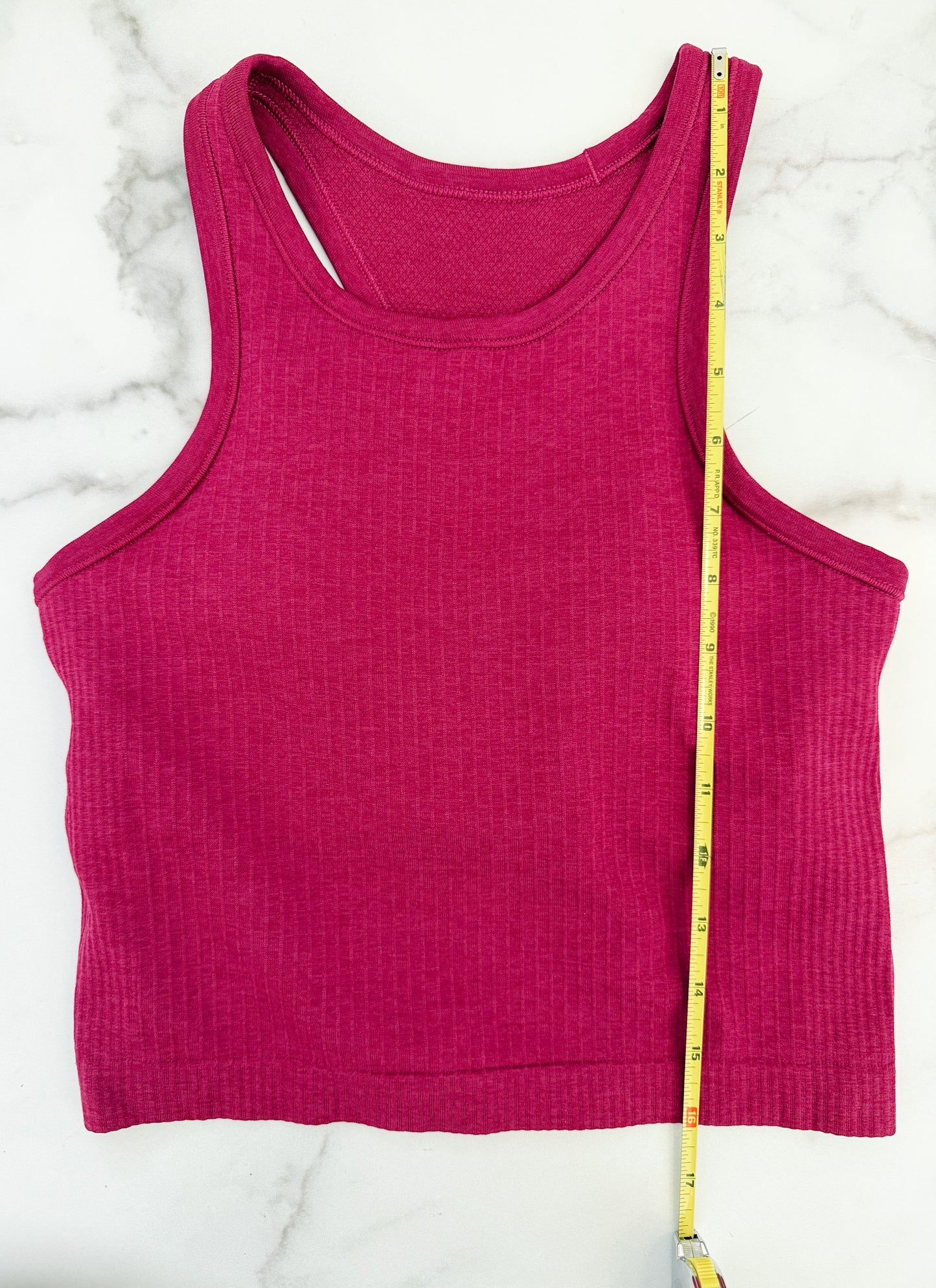 Pink tank top with a measuring tape on a white marble surface