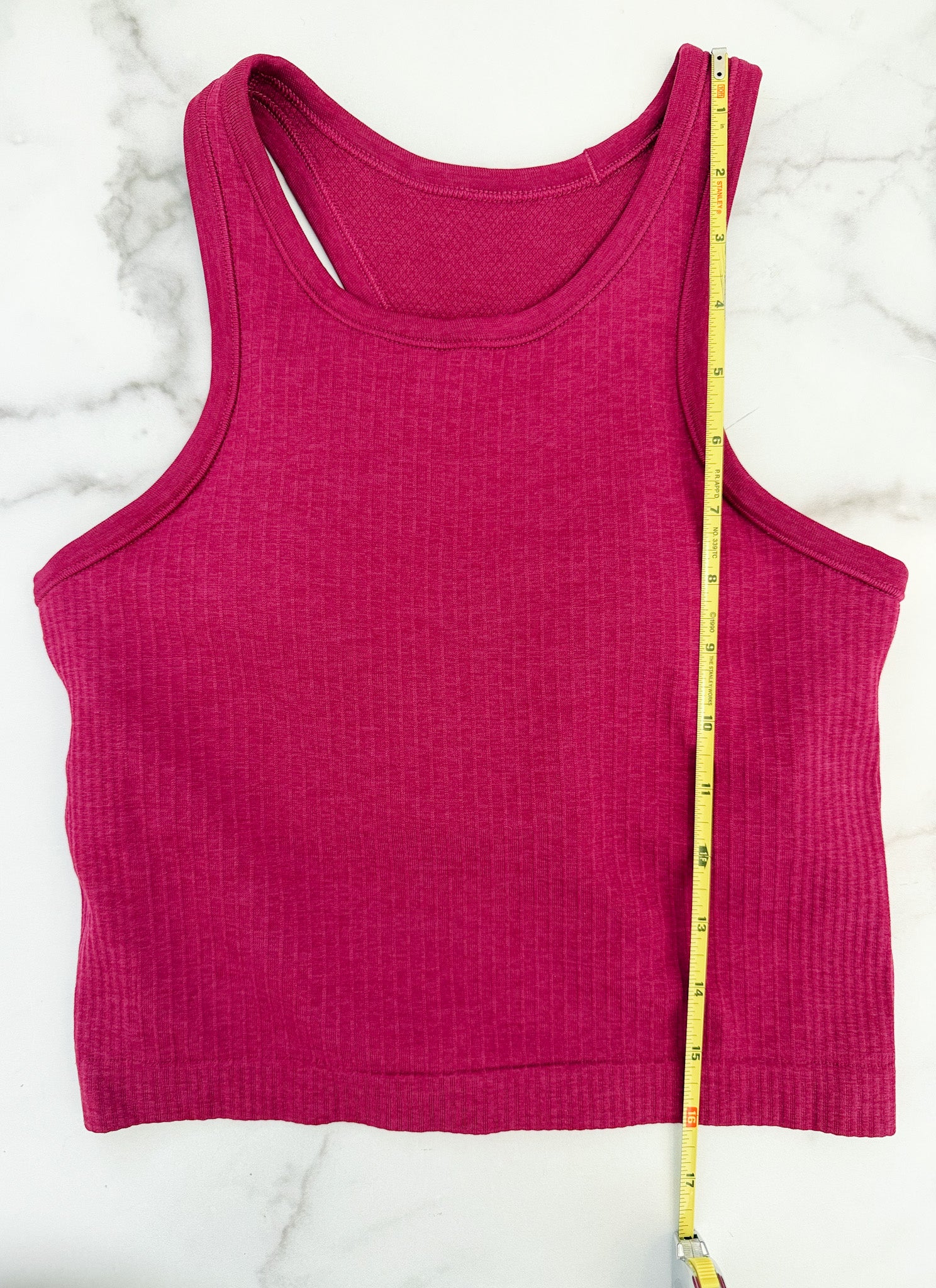 Pink tank top with a measuring tape on a white marble surface