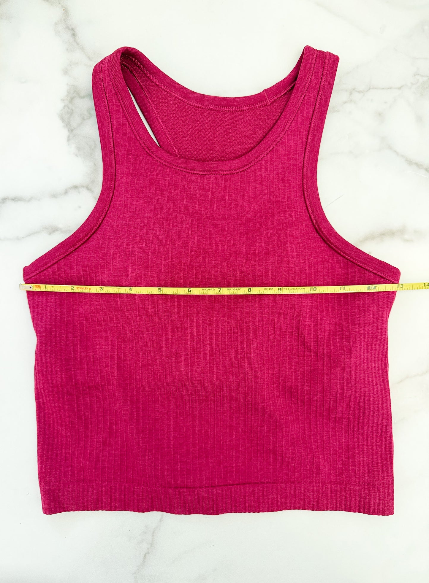 Pink tank top with a measuring tape on a white marble surface