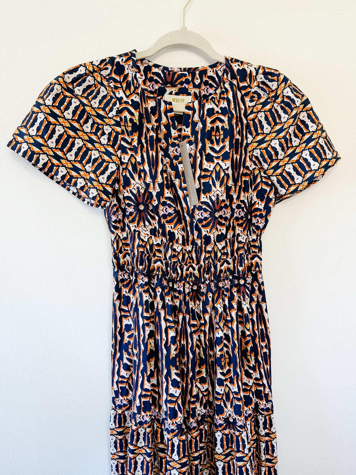 Patterned dress by Maeve on a hanger against a white background