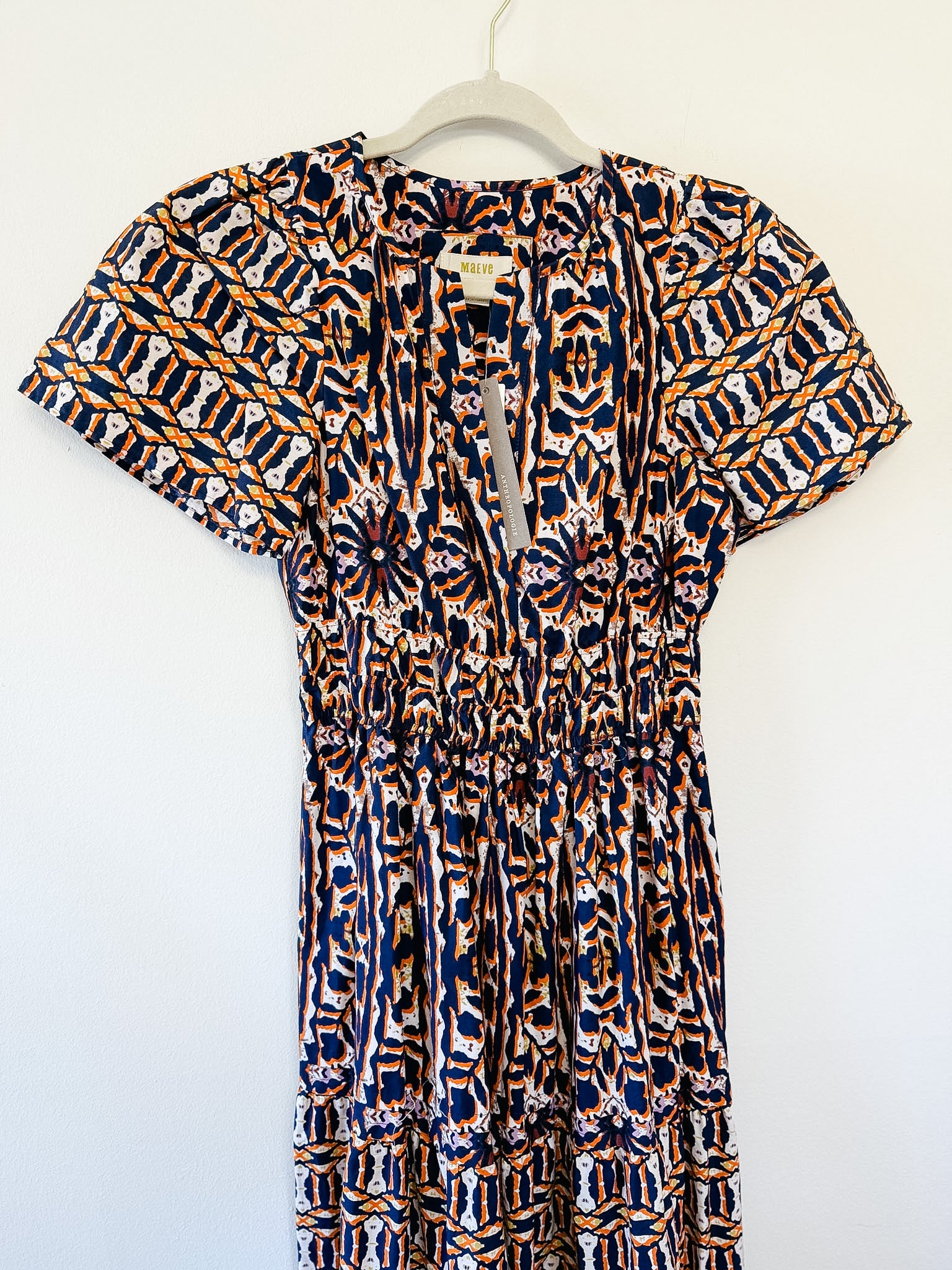 Patterned dress by Maeve on a hanger against a white background