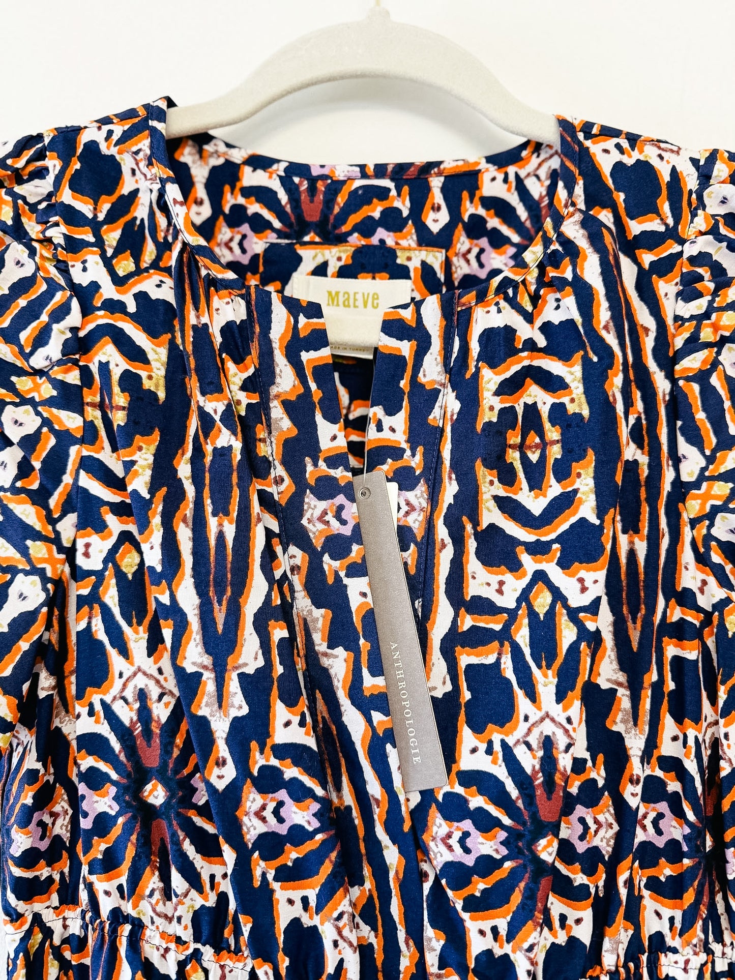 Patterned dress by Maeve on a hanger against a white background