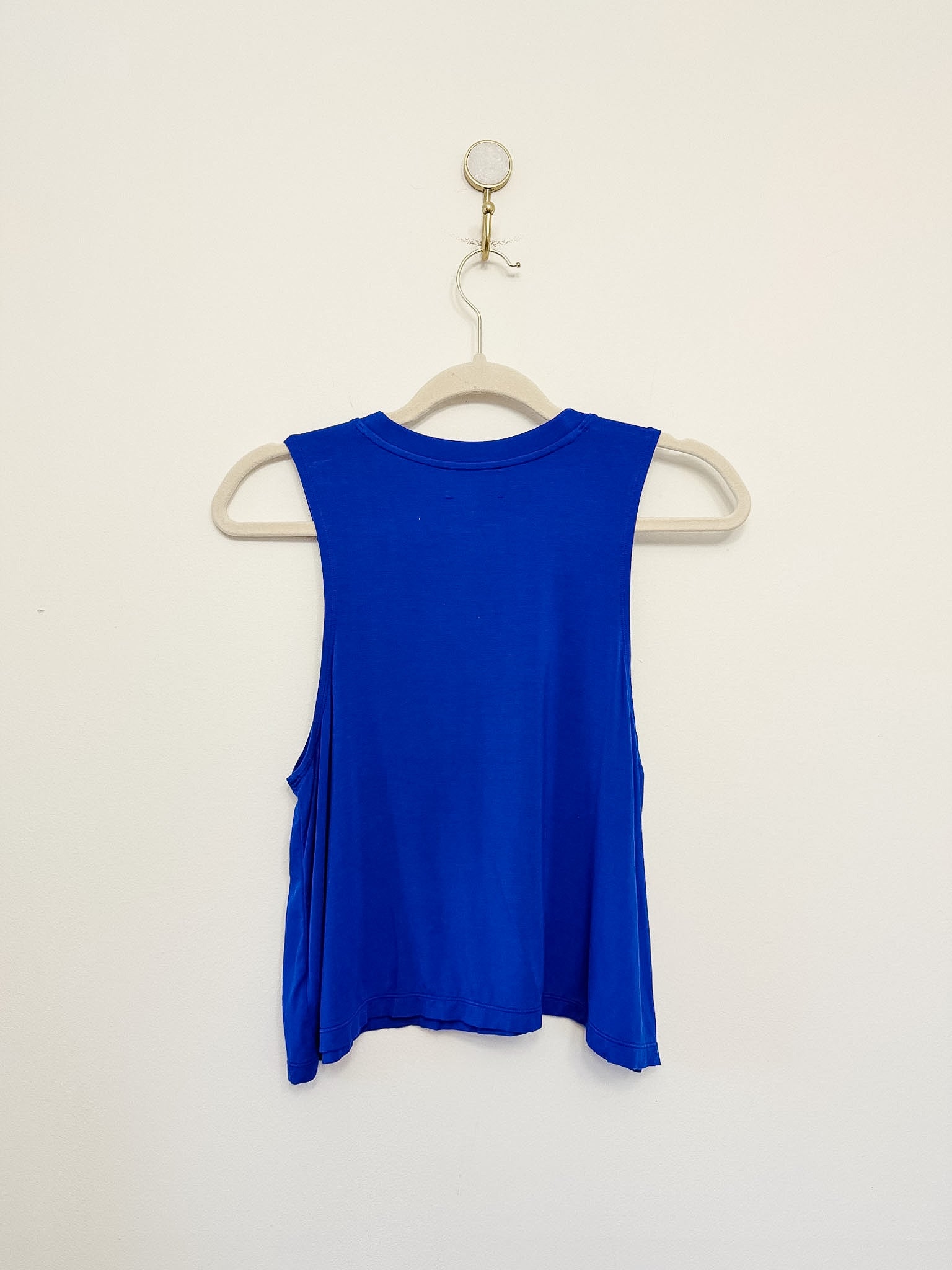 Carbon38 Crop Tank 2.0 blue sleeveless top on a hanger against a beige background