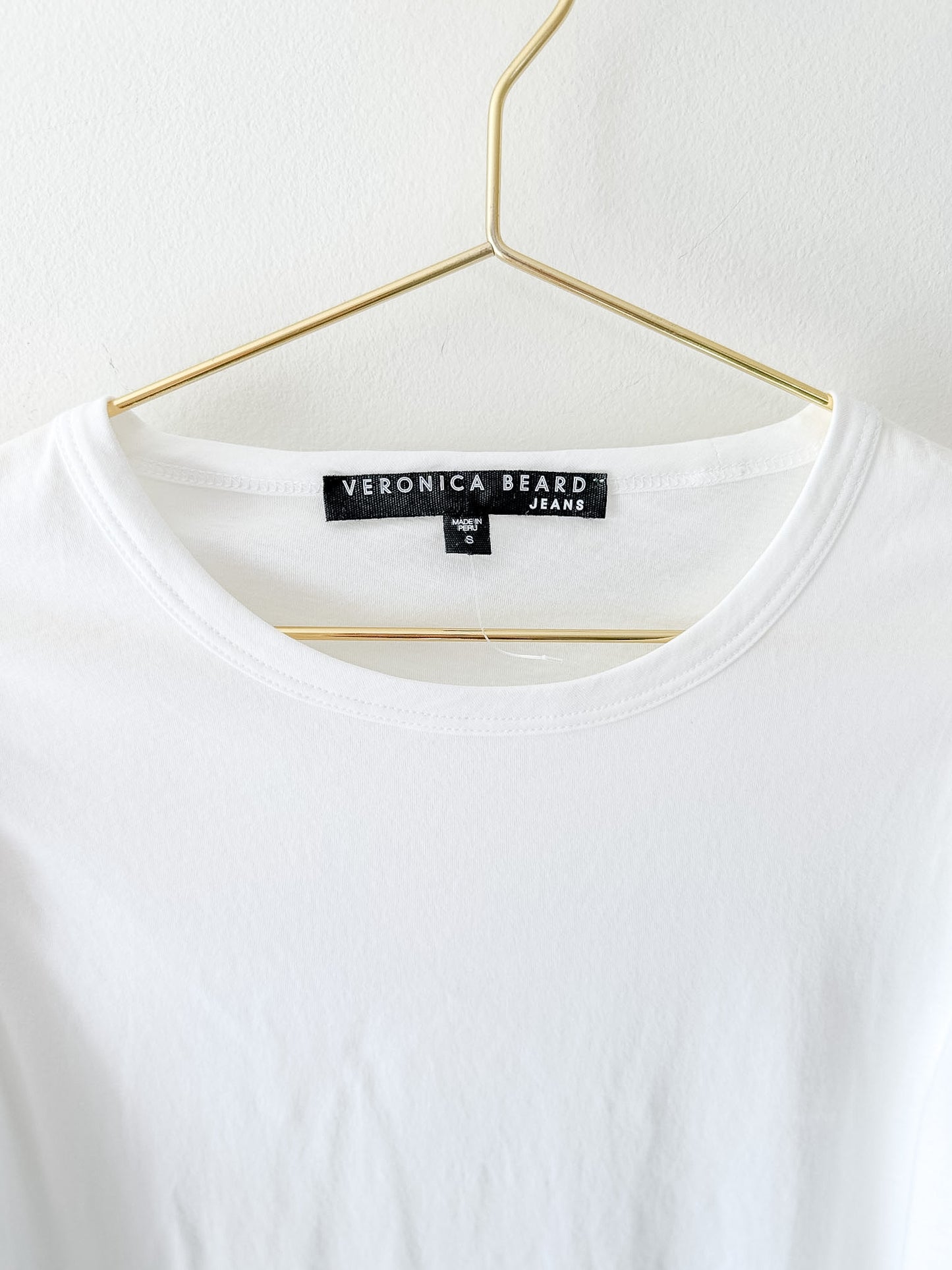 White t-shirt with 'Veronica Beard' label on a hanger against a white background