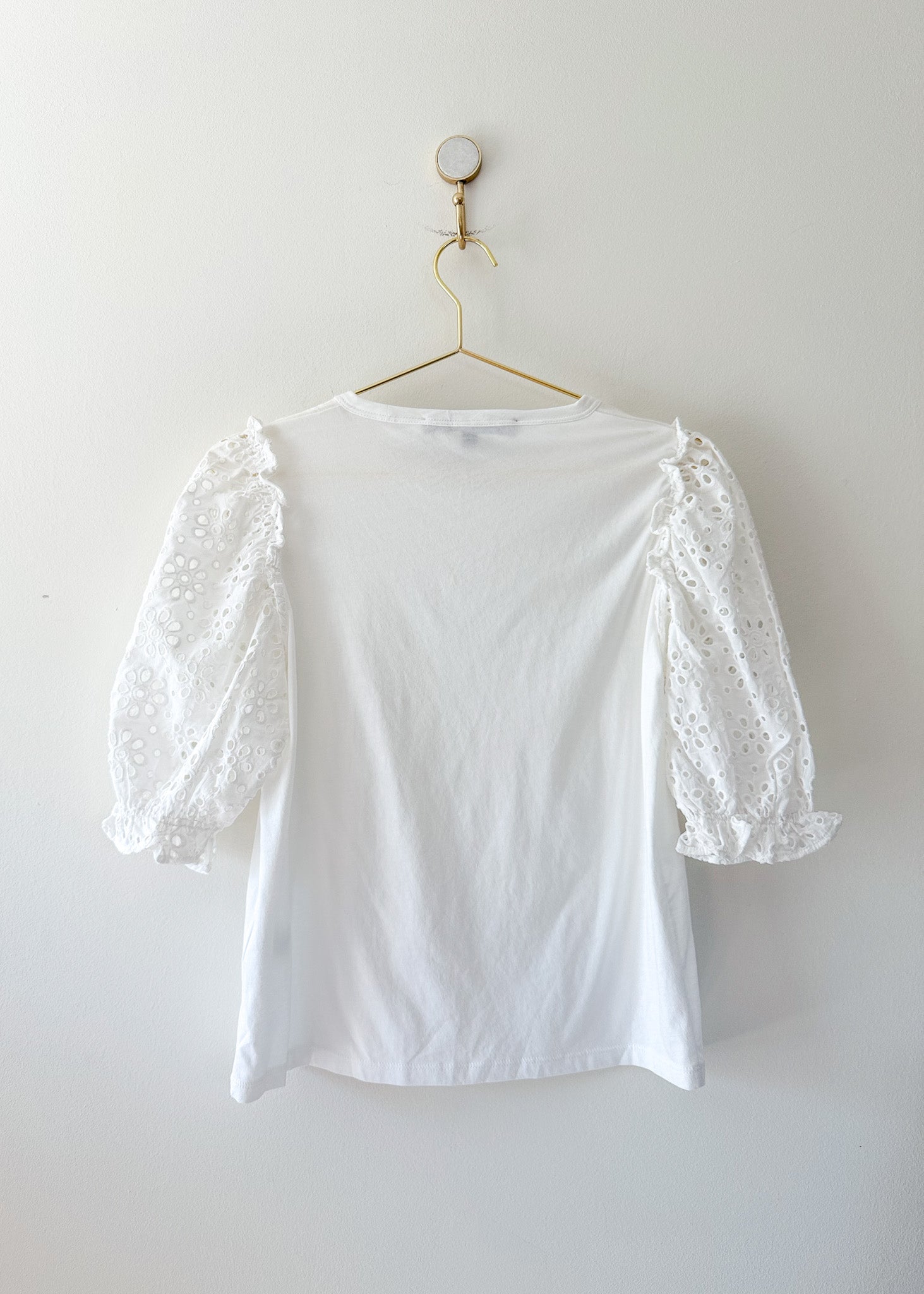 White Veronica Beard tee with eyelet sleeves on a gold hanger against a white background