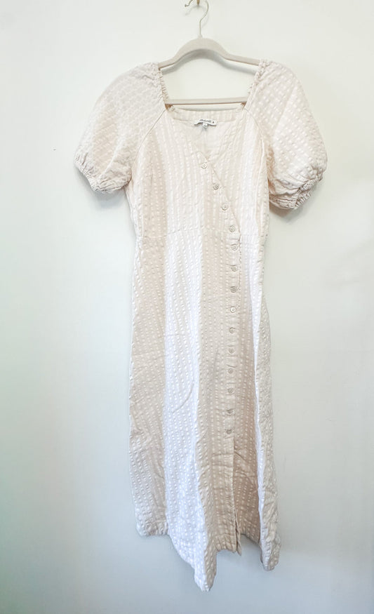 Tan and white Madewell dress on a hanger against a white background